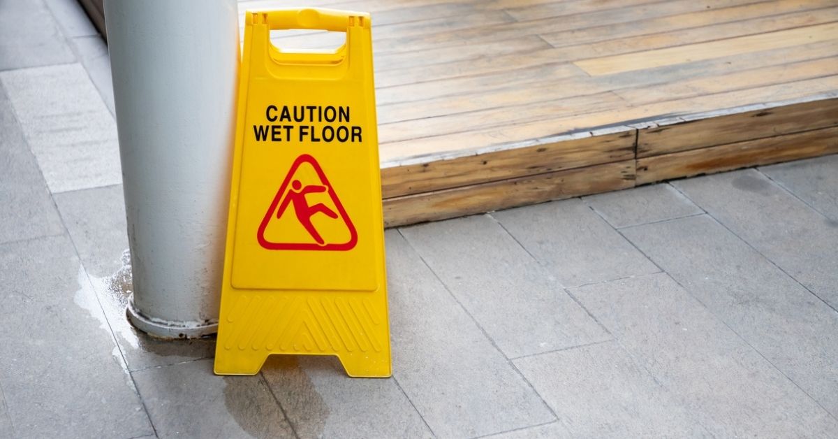 Wet floor sign with water drops on wet stone floor.
